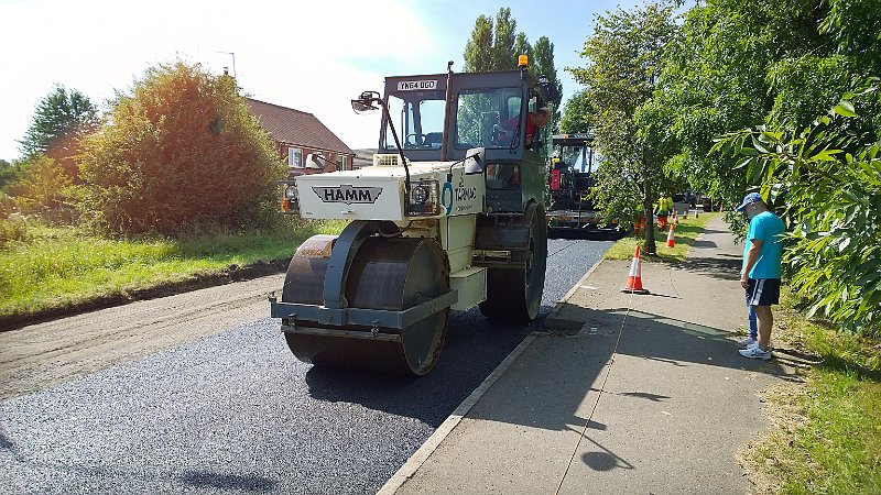 785-Laying.jpg - 785-Laying of the new road surface begins and the roller finishes the job